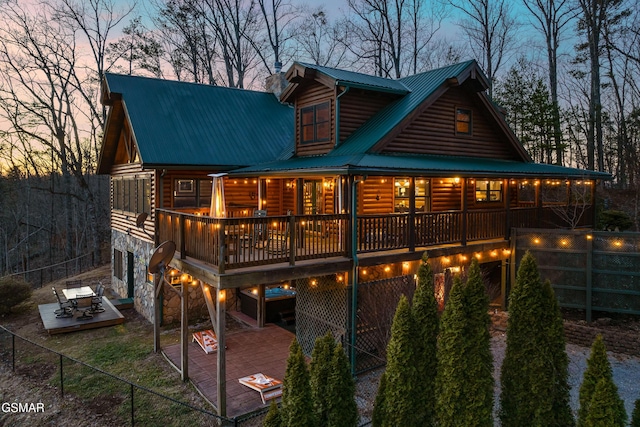 back of property featuring faux log siding, a deck, a patio area, and metal roof