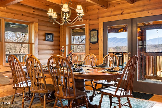 dining area featuring beamed ceiling, an inviting chandelier, wood finished floors, and a mountain view