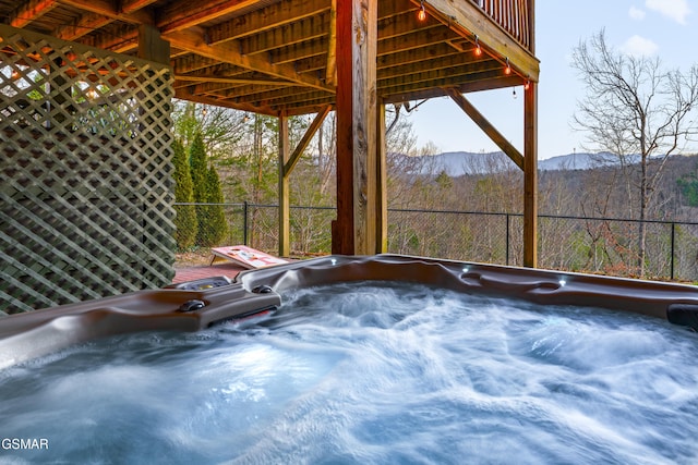 exterior space with a wooded view, a mountain view, and a hot tub