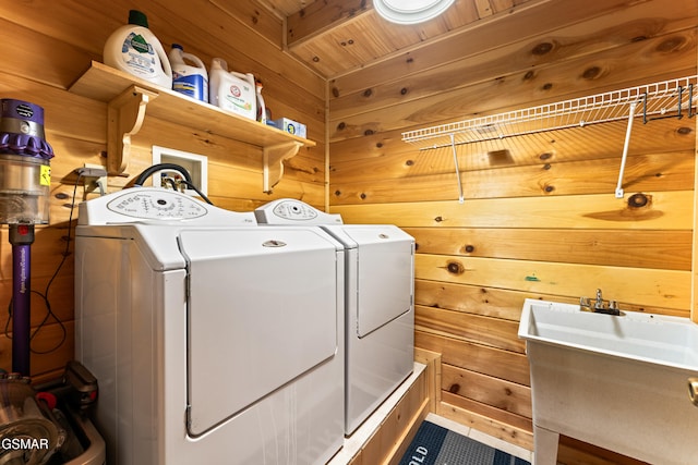 clothes washing area featuring separate washer and dryer, wood walls, and laundry area