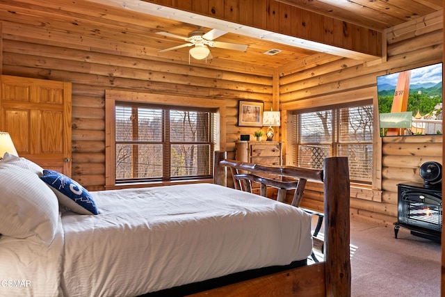 carpeted bedroom featuring visible vents, wood ceiling, and a wood stove