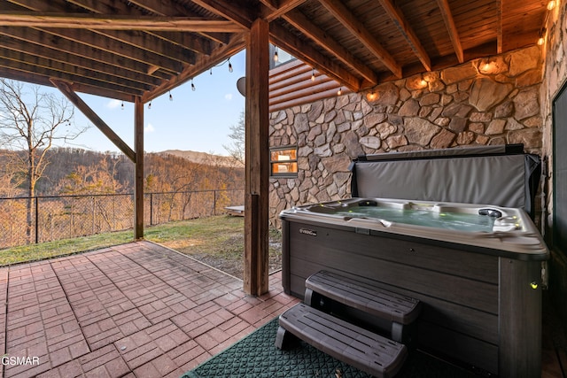 view of patio featuring fence, a mountain view, and a hot tub