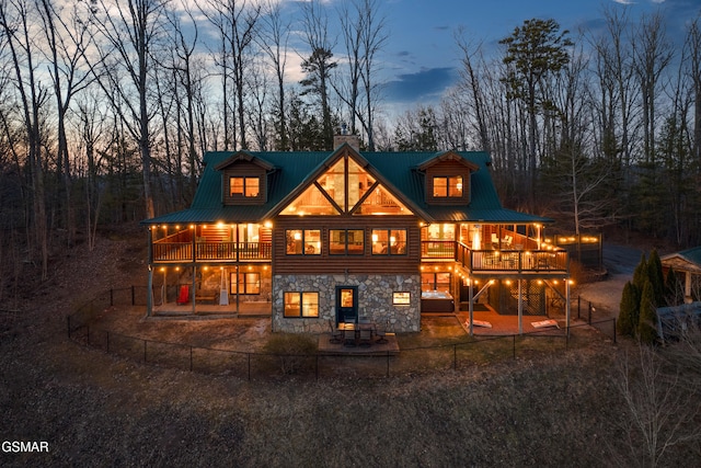 rear view of house with stone siding, metal roof, a patio, and a chimney