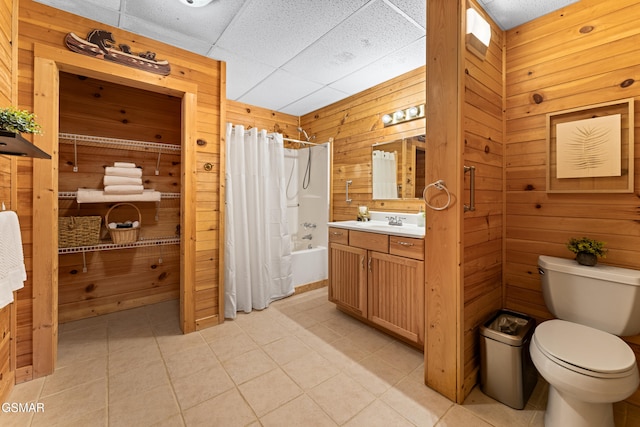 full bath with vanity, tile patterned flooring, shower / bath combo with shower curtain, wood walls, and toilet