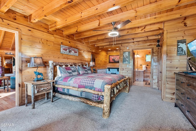 bedroom with carpet, beam ceiling, ensuite bathroom, and wooden walls