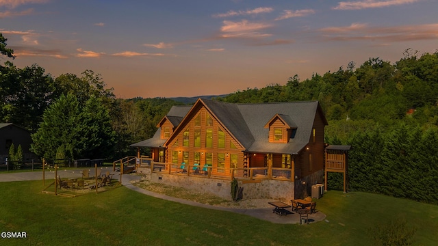 exterior space with central air condition unit, a fire pit, and a lawn