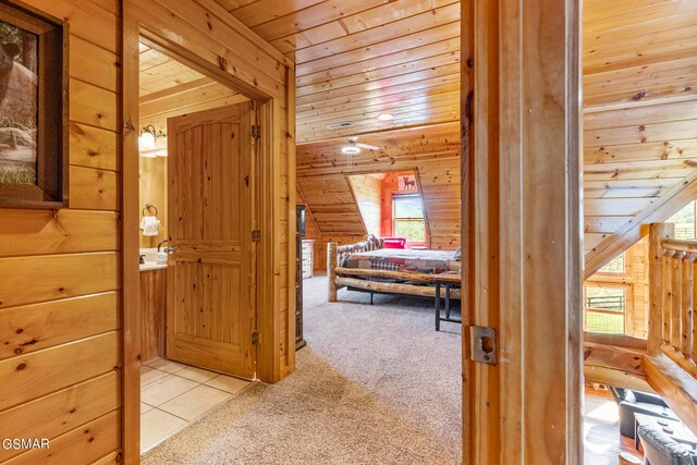 hall featuring light colored carpet, vaulted ceiling, wooden ceiling, and wood walls