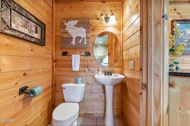 bathroom featuring tile patterned flooring, toilet, and wooden walls