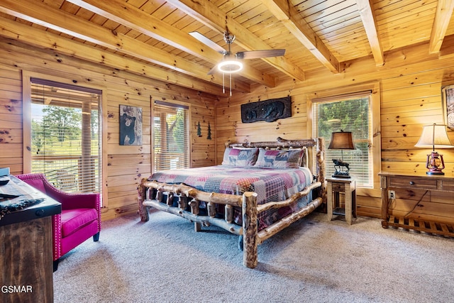 carpeted bedroom with beamed ceiling, multiple windows, and wooden walls