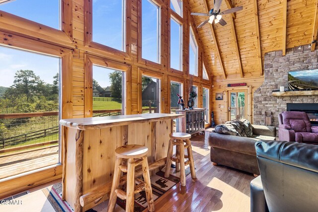 sunroom / solarium featuring vaulted ceiling with beams, ceiling fan, plenty of natural light, and wood ceiling