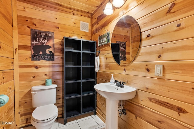 bathroom with tile patterned floors, wood walls, toilet, and sink