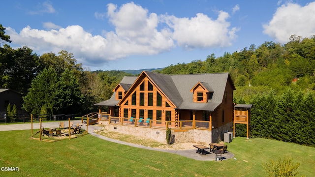 rear view of house with a yard, a fire pit, and a wooden deck