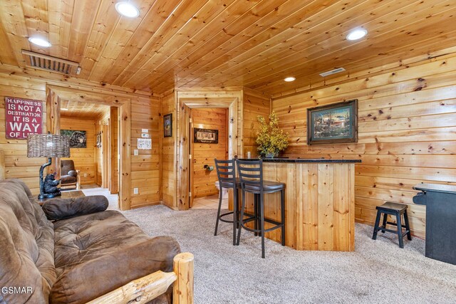 bar featuring wood walls, light brown cabinets, wooden ceiling, and light carpet