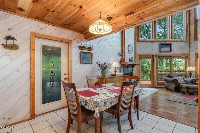 dining space featuring a fireplace, light tile patterned floors, wood ceiling, and a chandelier