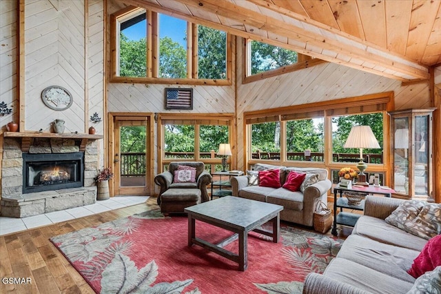 living area featuring high vaulted ceiling, wooden walls, hardwood / wood-style floors, and a fireplace