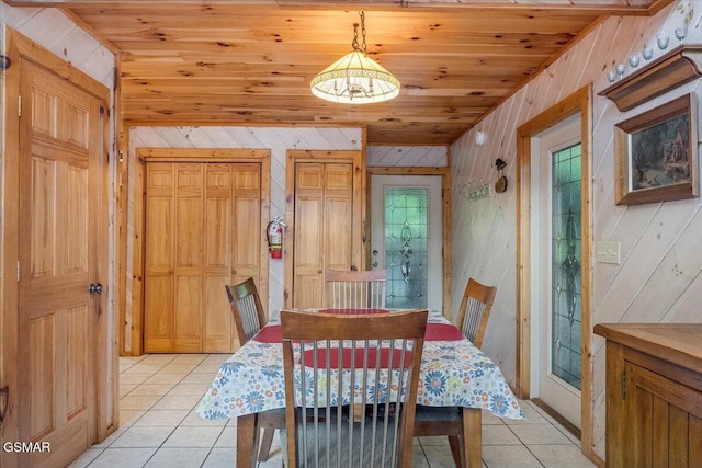 dining room featuring wood ceiling, light tile patterned flooring, and wood walls