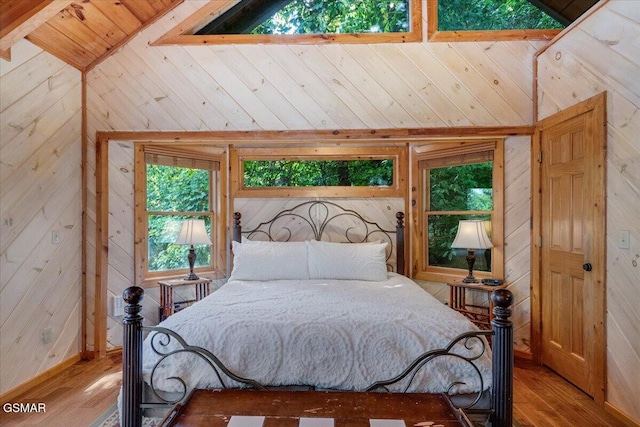 bedroom with wood walls, wood finished floors, and vaulted ceiling