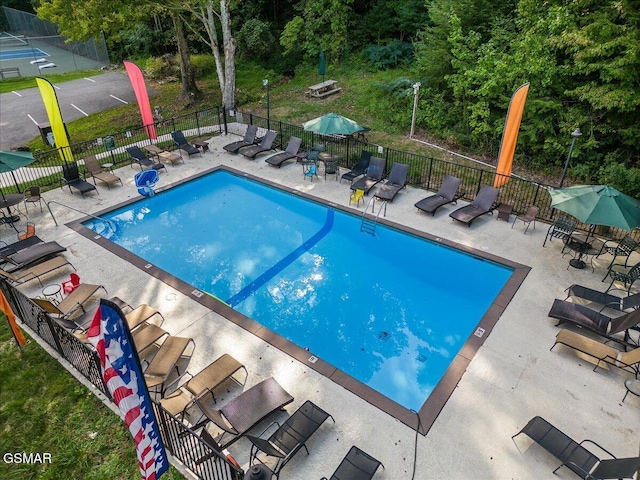 pool with a patio area and fence