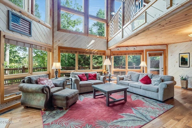 living room featuring wood-type flooring, wooden walls, and a high ceiling