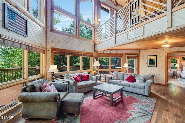 living room with wooden walls, a high ceiling, and hardwood / wood-style floors