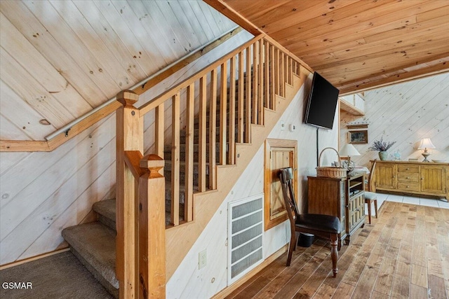 stairs with wooden walls, wood ceiling, and hardwood / wood-style floors