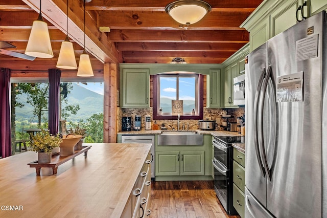 kitchen with appliances with stainless steel finishes, butcher block countertops, and green cabinetry