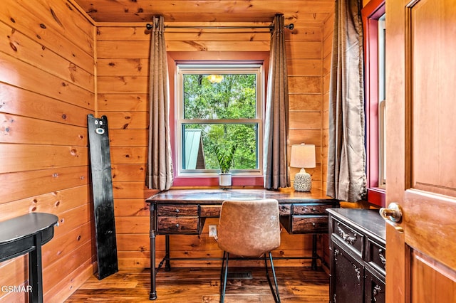 office space with wooden walls, built in desk, and wood-type flooring