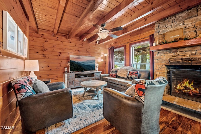 living room featuring beam ceiling, hardwood / wood-style flooring, wooden ceiling, a stone fireplace, and wood walls