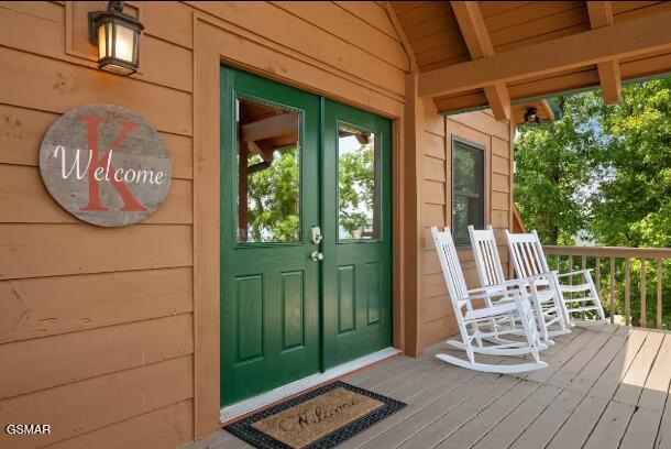 view of exterior entry featuring french doors and a porch