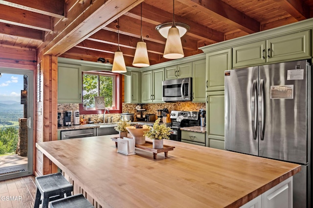 kitchen with wood counters, appliances with stainless steel finishes, beam ceiling, green cabinetry, and hanging light fixtures