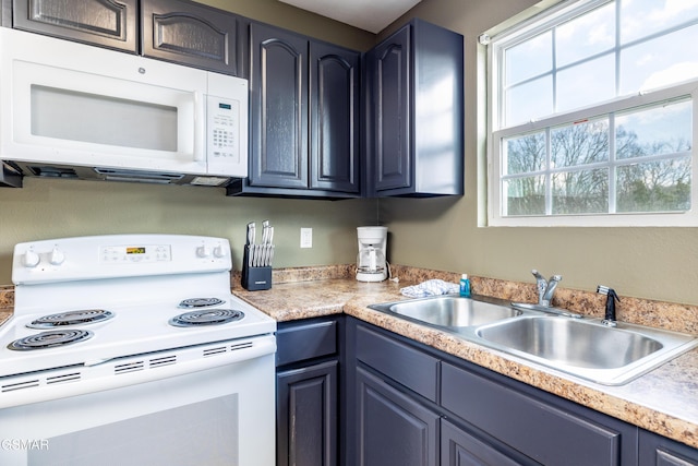 kitchen with blue cabinetry, white appliances, light countertops, and a sink