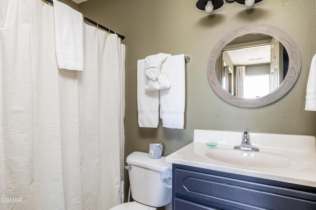 bathroom with toilet, vanity, and a textured wall