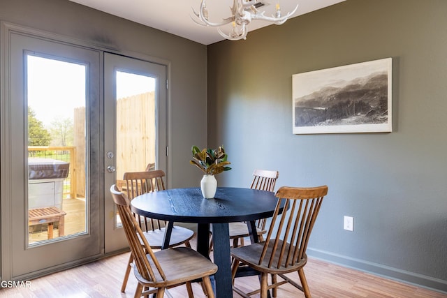 dining area featuring french doors, baseboards, an inviting chandelier, and light wood finished floors