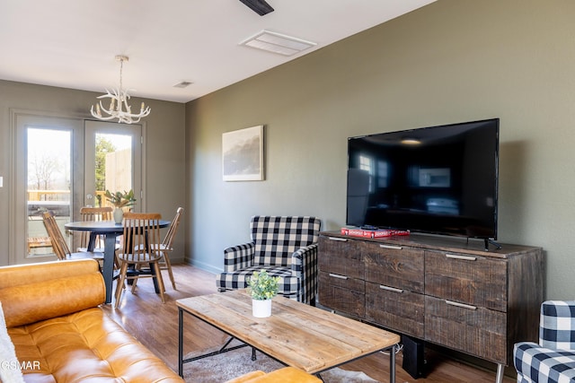 living area featuring visible vents, an inviting chandelier, and wood finished floors