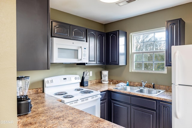 kitchen with a sink, visible vents, white appliances, and light countertops