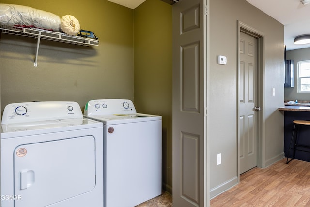 laundry area featuring washer and dryer, baseboards, light wood-style flooring, and laundry area