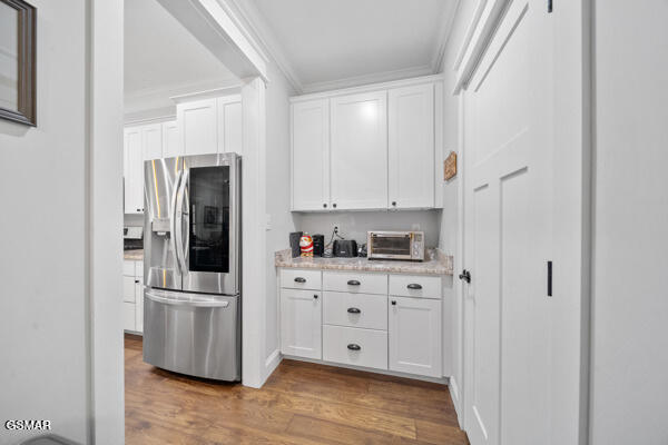kitchen with wood finished floors, white cabinets, a toaster, and stainless steel fridge with ice dispenser
