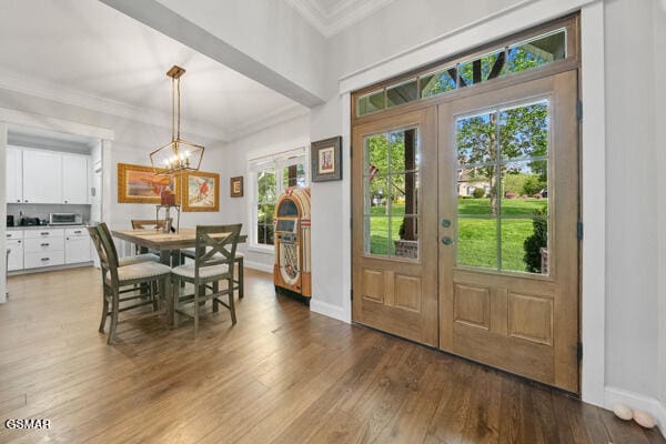 entryway with french doors, ornamental molding, wood finished floors, and an inviting chandelier