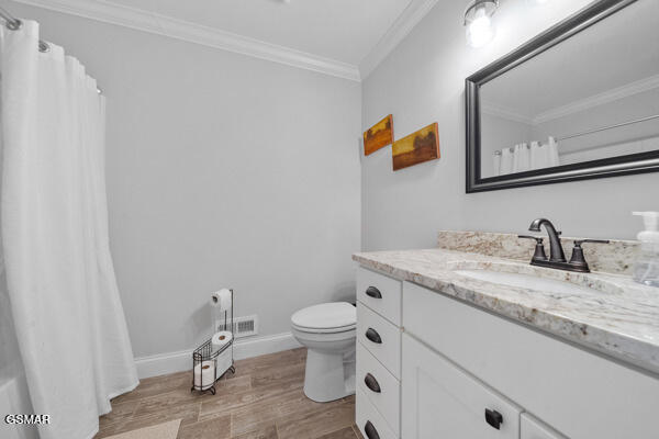bathroom with vanity, ornamental molding, wood finished floors, curtained shower, and toilet