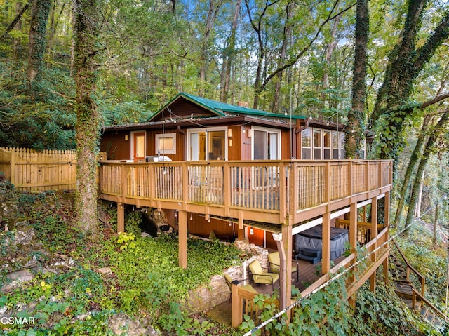 rear view of property featuring a hot tub and a deck