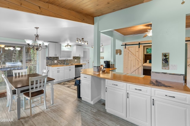 kitchen with white cabinetry, dishwasher, hanging light fixtures, a barn door, and backsplash