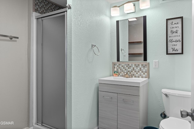 bathroom featuring backsplash, vanity, an enclosed shower, and toilet