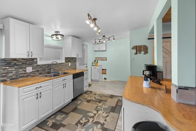 kitchen with white cabinetry, sink, stainless steel dishwasher, wooden counters, and backsplash