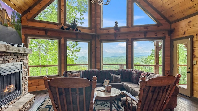 living room featuring wooden walls, a fireplace, lofted ceiling, and hardwood / wood-style floors