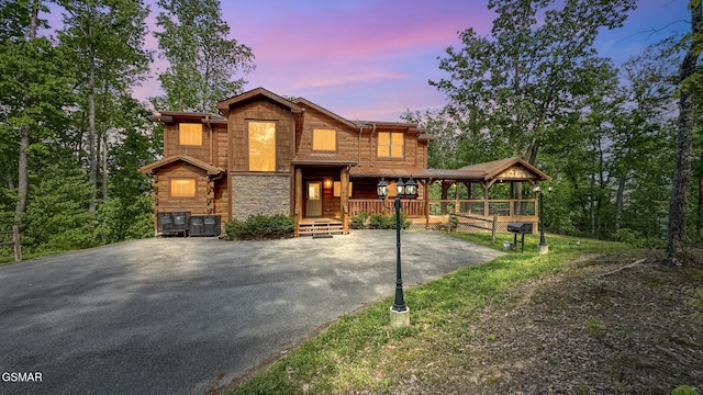 view of front of property featuring stone siding, aphalt driveway, and covered porch