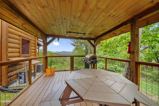 wooden deck featuring a mountain view, outdoor dining space, and grilling area