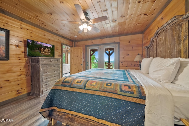 bedroom featuring french doors, wood walls, wood finished floors, and access to exterior