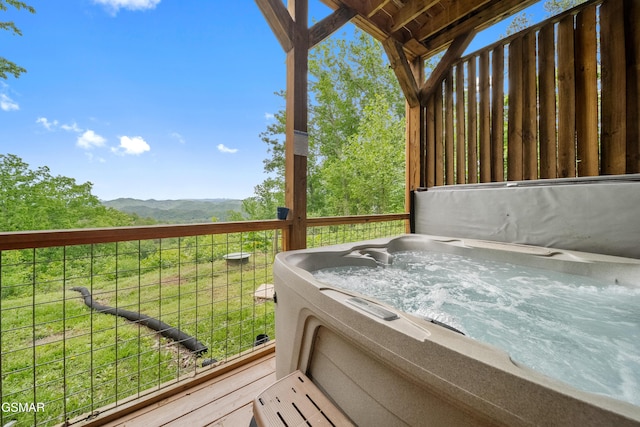 deck featuring a hot tub and a mountain view