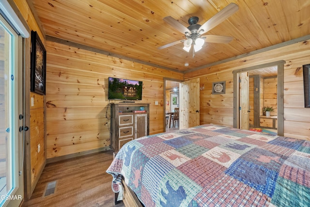 bedroom with wooden walls, wood ceiling, visible vents, and wood finished floors