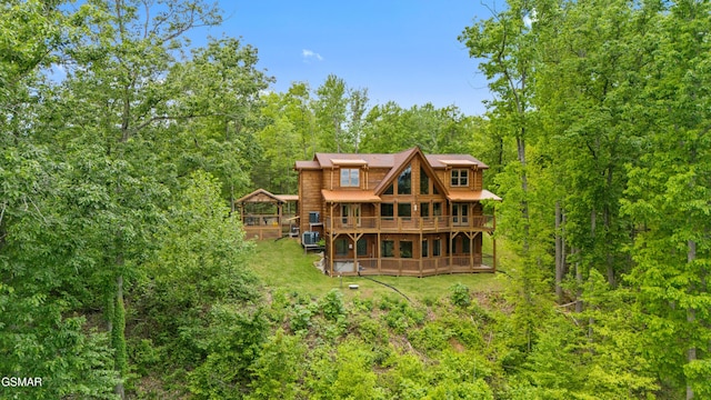 back of property featuring a yard, a view of trees, and a wooden deck